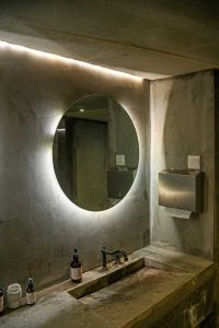 Hinterleuchterter Spiegel über einem Waschbecken. Das Licht sorgt für Kontrast und gibt klare Linien.